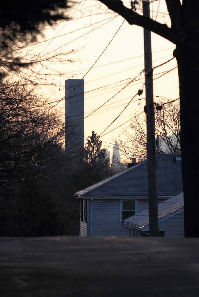 An elevator shaft rises from the former Symmes site in the morning sun. In this view down Hemlock Street, the silhouette of the Customs House Tower in Boston can also be seen.November