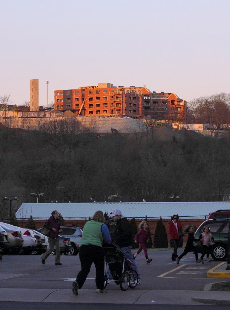 A worker stands in the sunset atop the new construction at the former Symmes site as the rest of the people Arlington below go about their business.December 14, 2012.