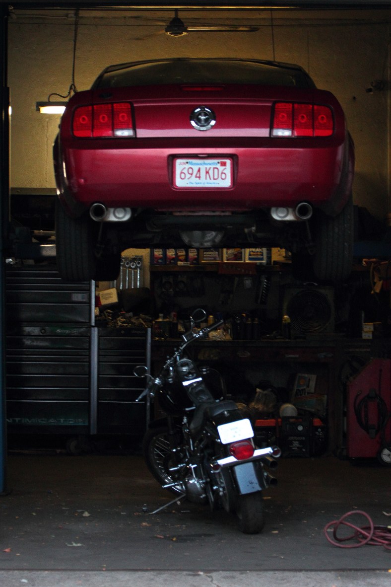 A motorcylcle is parked under a Mustang in the garage of Brown Automotive on Massachusetts Avenue.August 31, 2012.