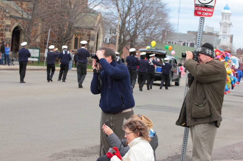 People snap their last photographs as the tail end of the Patriots' Day parade passes by. April 14, 2013.