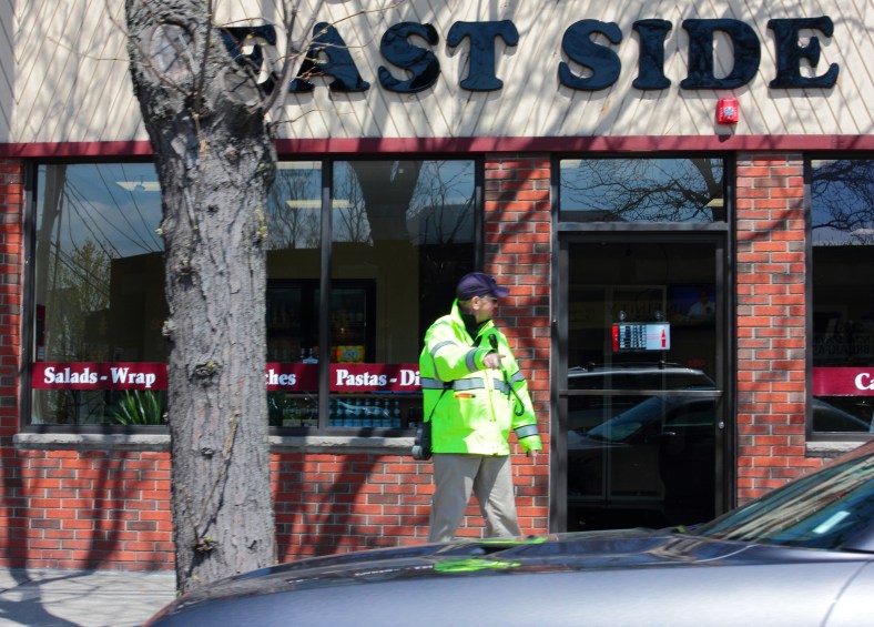 A traffic officer motions to a parked car as he yells to a citizen down the sidewalk outside of the new Anthony's East Side Deli on Massachusetts Avenue. April 26, 2013.