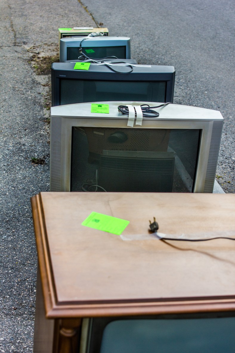 Televisions of various sizes and sytles, with proper CRT/TV disposal stickers from the town, line the sidewalk on Jason Street. May 11, 2013.