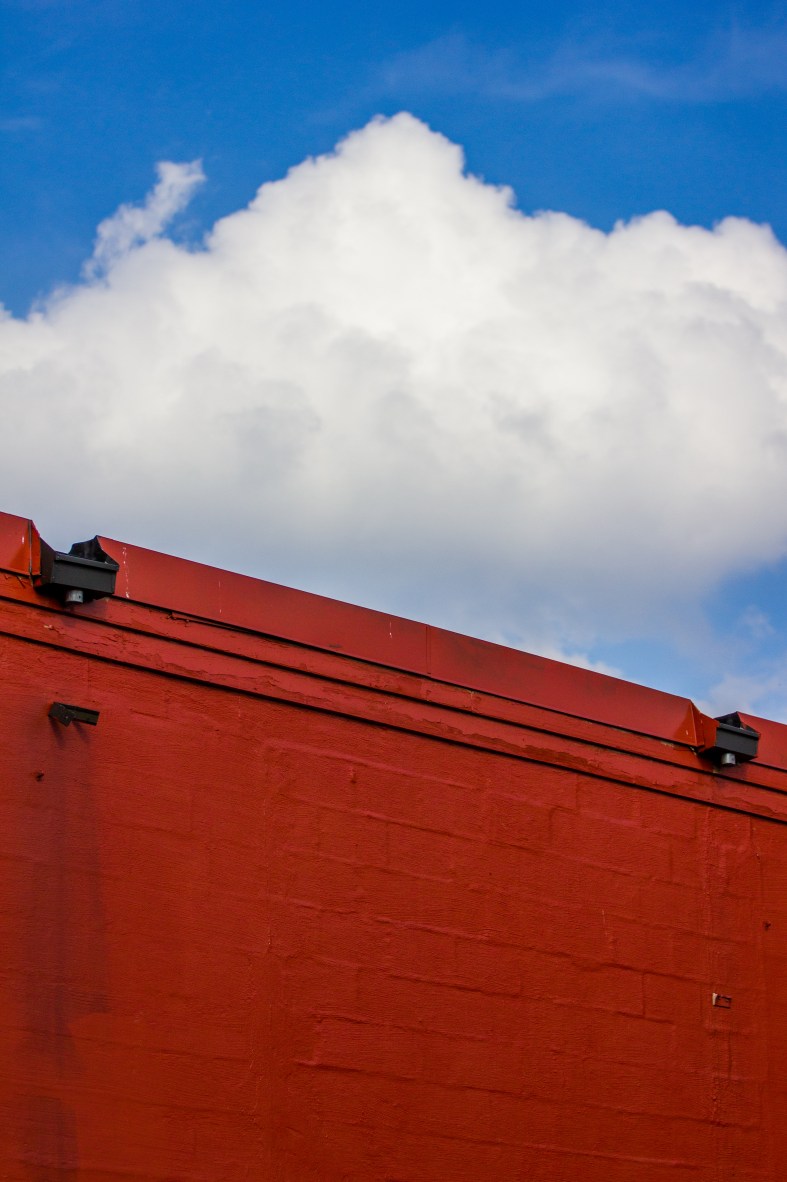 The blue sky contrasts the color of the back wall of a Summer Street building as seen from the bike path. September 12, 2013.