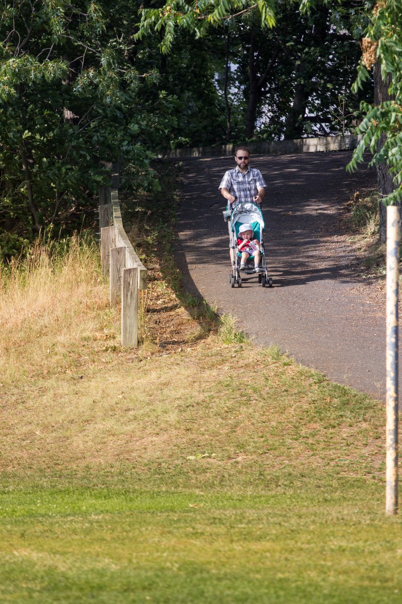 A man guides his child in a stroller down the ramp off the bike path to Spy Pond Field. September, 12, 2013.
