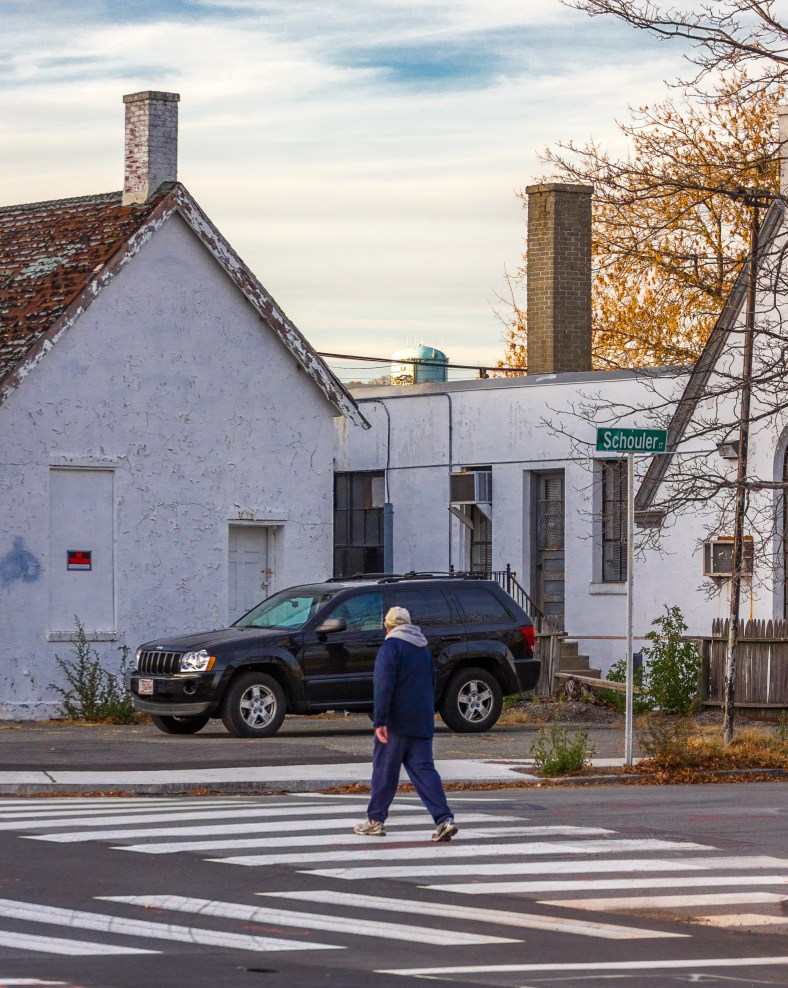 A man crosses Schouler Court while the green Turkey Hill water tower can be seen in the distance. November 15, 2013.