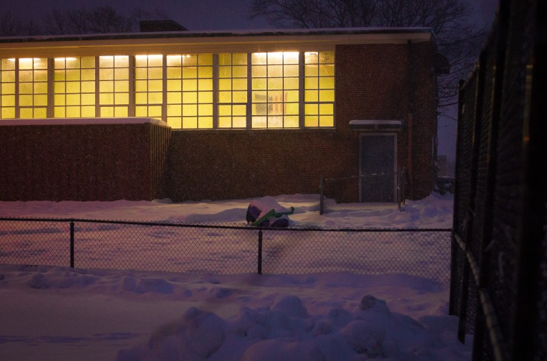 The American flag can be seen hanging in the lit gymnasium of the Stratton Elementary School on a snowy night. December 17, 2013.