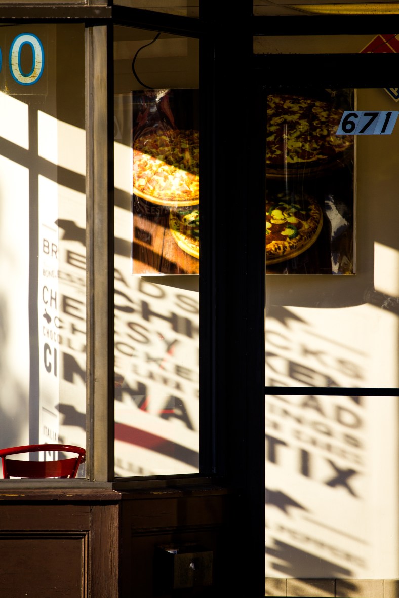 The late afternoon sun casts the shadows of advertisements on the Dominos Pizza location in Arlington Center. September 12, 2012.