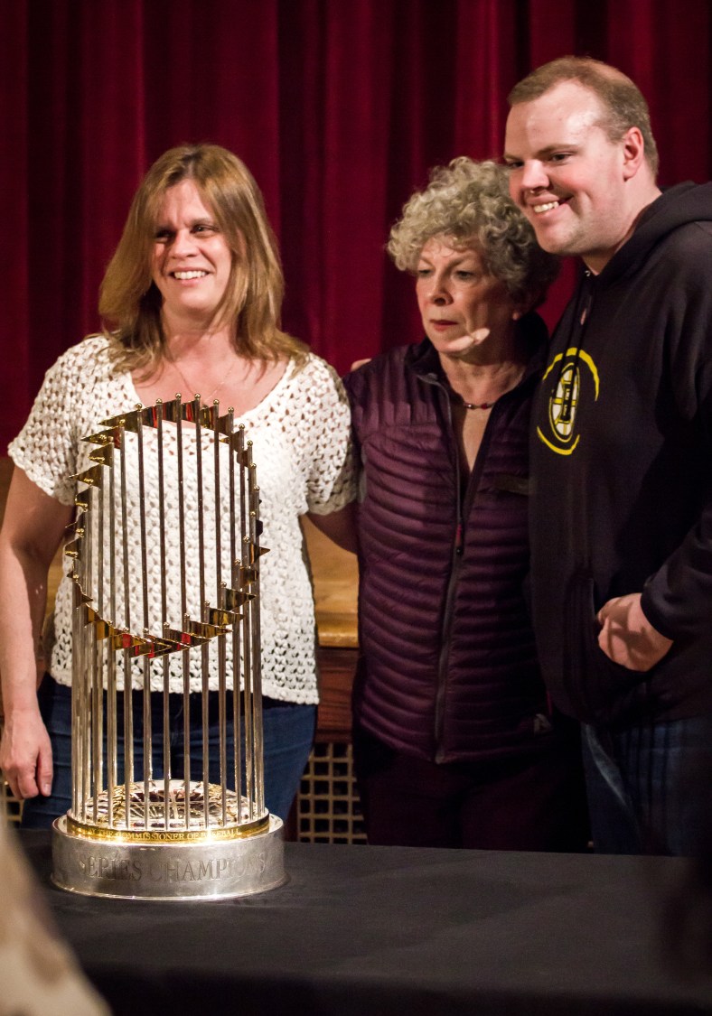 Women pose with State Rep. Sean Garballey and the World Series trophy from the 2013 championship season of the Boston Red Sox during a showing at Town Hall. March 29, 2014.
