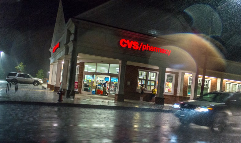 An employee vacuums the entrance of the CVS on Massachusetts Avenue while customers take shelter from a hard rain. August 31, 2014.