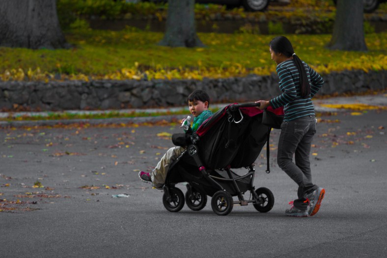 A young boy in a stroller checks to make sure there are no cars coming his way as he is pushed across the street. October 17, 2014.