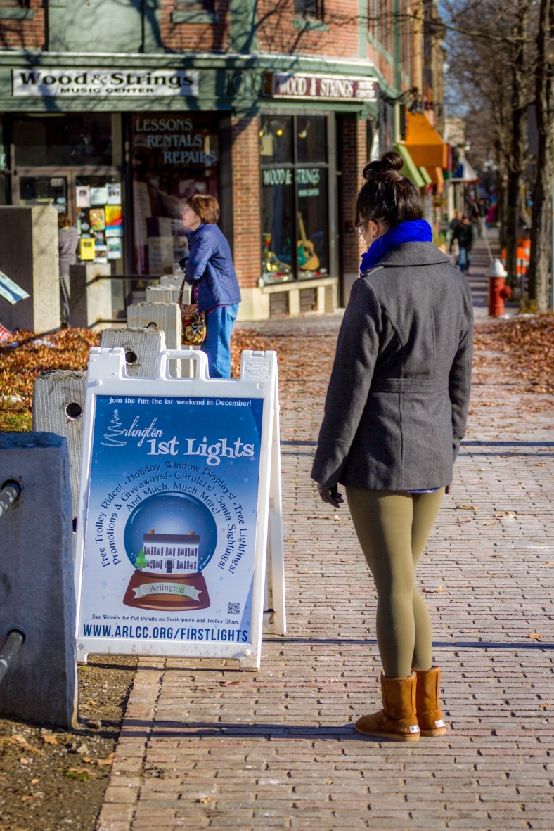 A woman stops to read the Arlington Lights sign while another admires the scene of the Jefferson Cutter House and Whittemore Park. November 29, 2014.