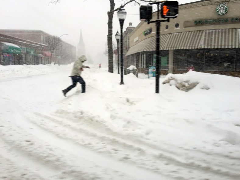 A person hops up onto the snowbank blocking the sidewalk at the corner of Medford Street and Massachusetts Avenue. February 2, 2015.