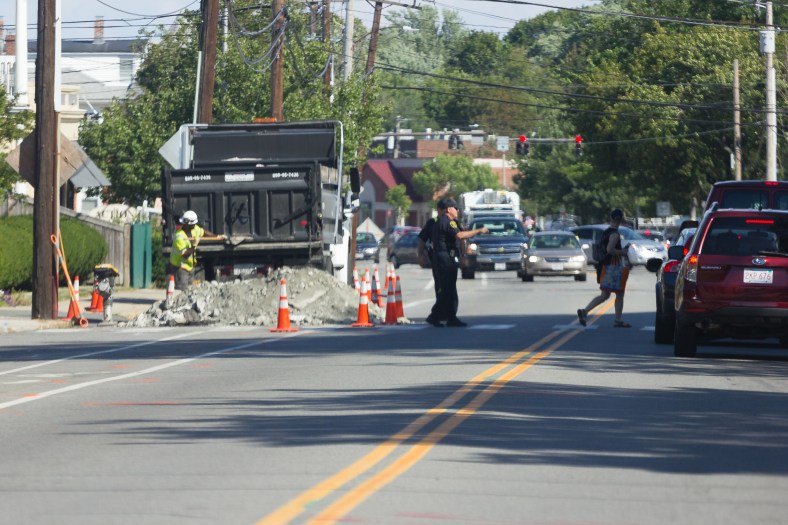 A police officer aids a pedestrian in crossing Massachusetts Avenue near a road work site. August 05, 2015.